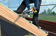 Eine Person arbeitet auf einem Dach mit einer elektrische Säge.