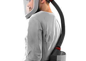 Eine Person trägt einen grauen Anzug und einem gebläseunterstützten Filtergeräte mit Schutzhelm. Dieser bietet als Persönliche Schutzausrüstung einen hohen Schutz gegen mehrfache Gefährdungen.