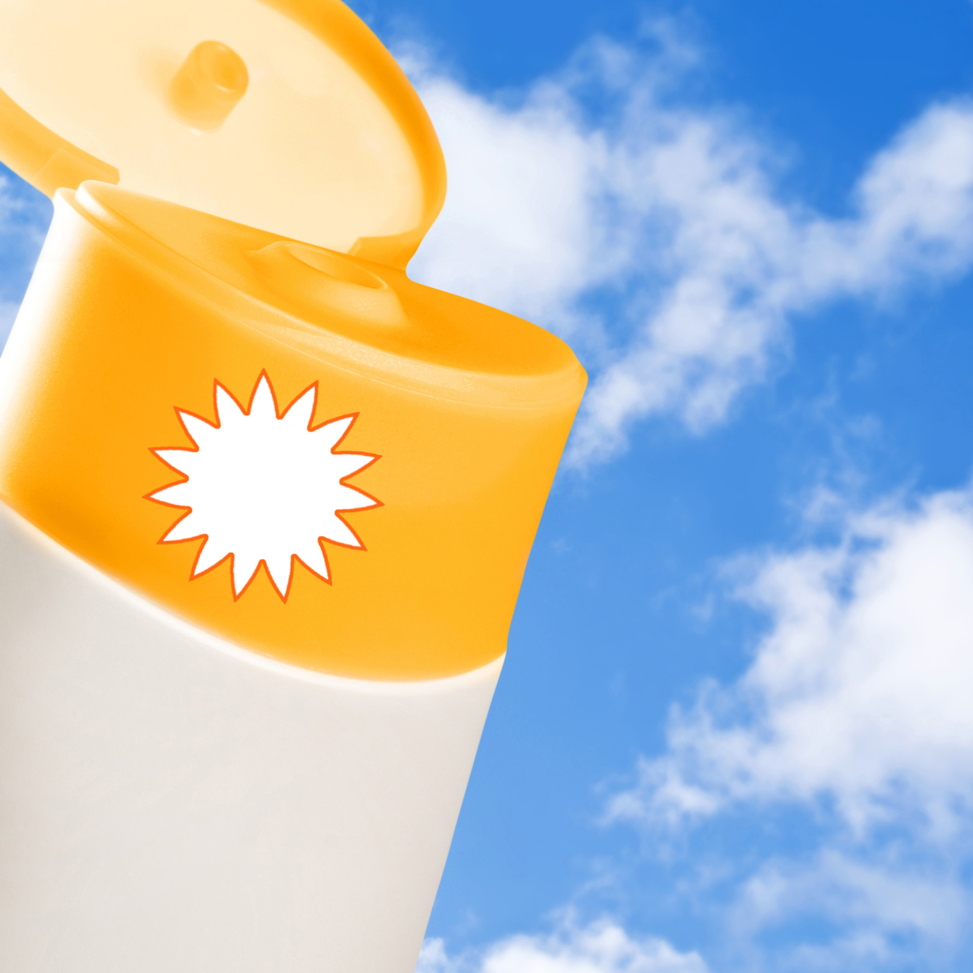 Eine Flasche mit Sonnencreme vor einem blauen Himmel mit Sonnenschein.