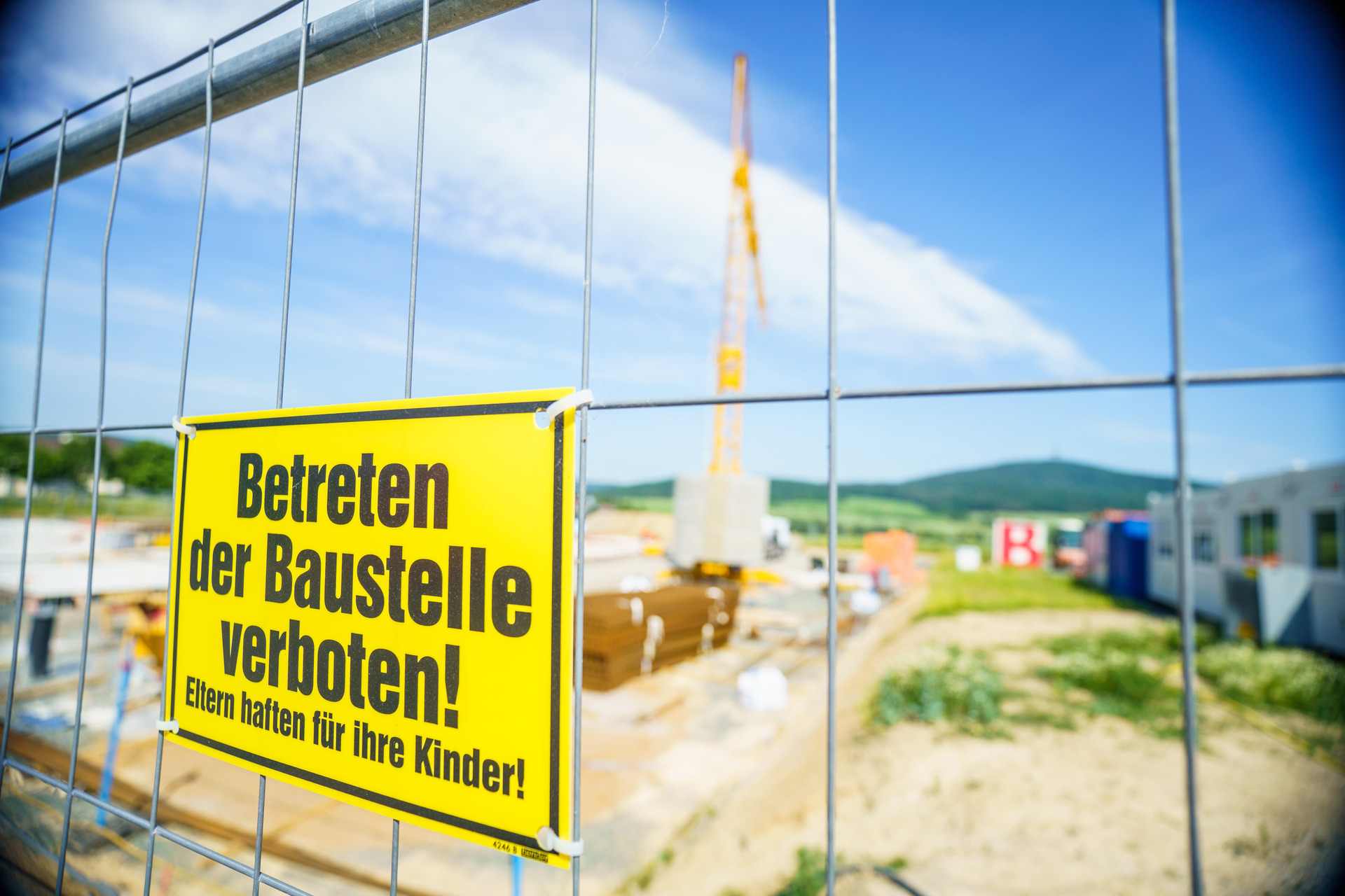 Gelände einer Baustelle mit gelbem Schild am Zaun: Betreten der Baustelle verboten! Eltern haften für ihre Kinder!