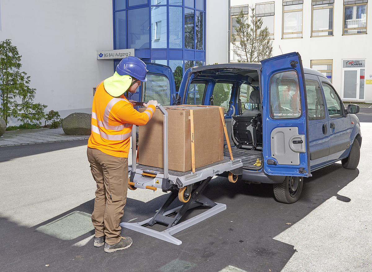 Ein Mann belädt einen Transportwagen mithilfe einer Hebehilfe