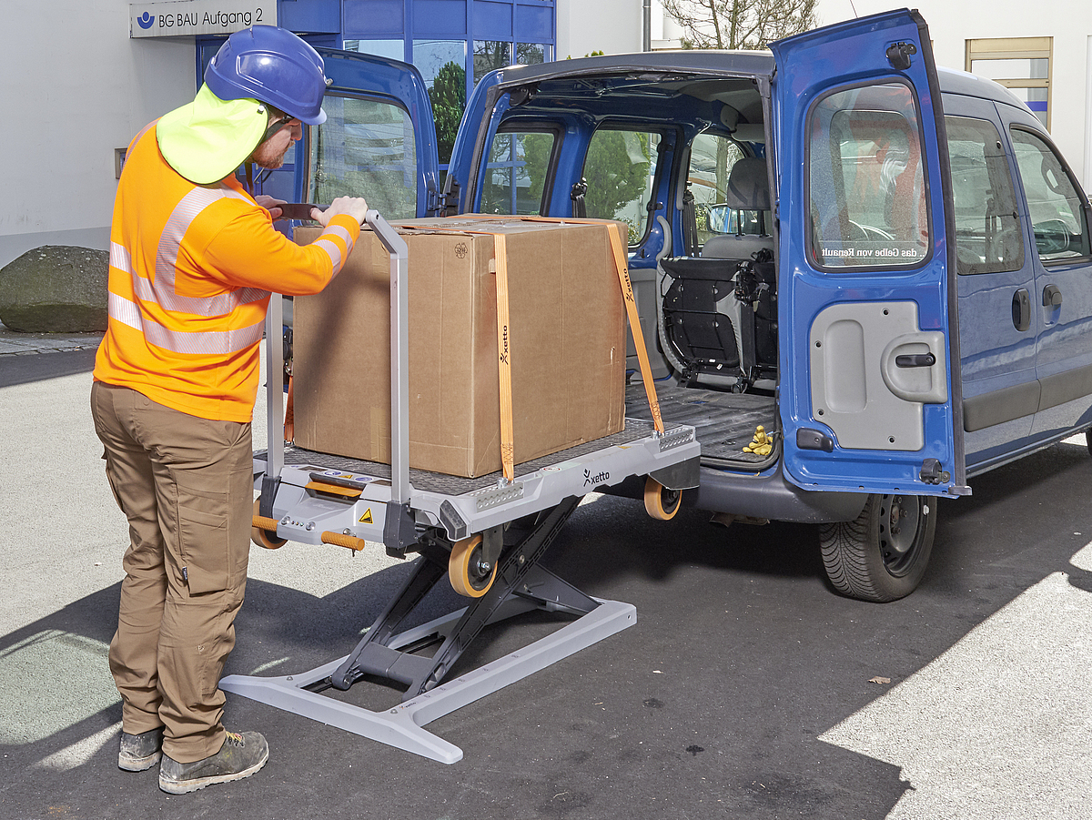 Ein Mann bel&auml;dt einen Transportwagen mithilfe einer Hebehilfe