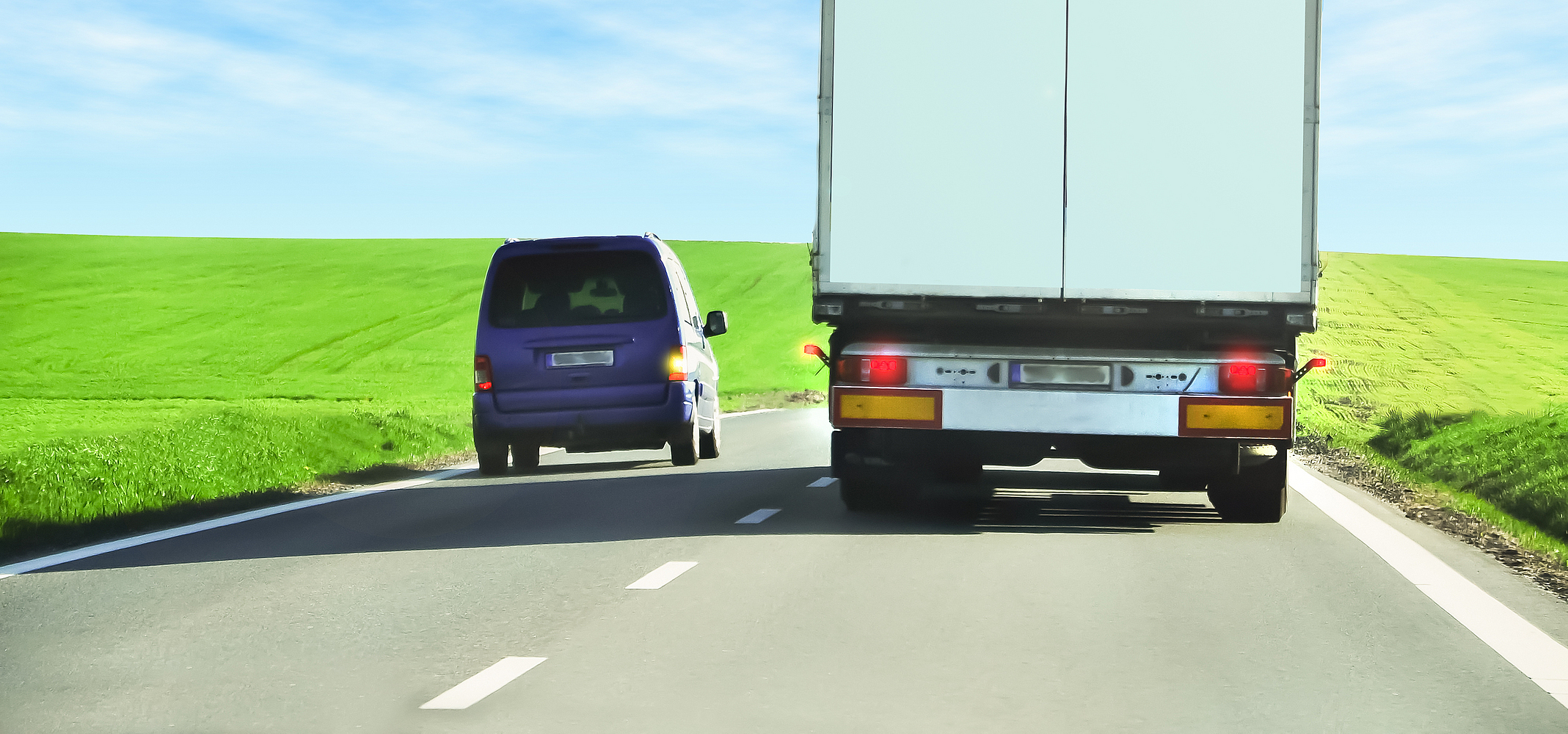 Ein Pkw überholt einen Lkw auf einer Landstraße.