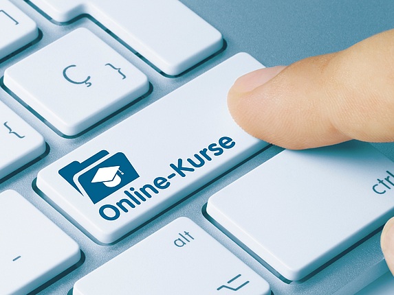 Ein Finger zeigt auf einer Tastatur auf eine Taste mit der Aufschrift „Online-Kurse“.