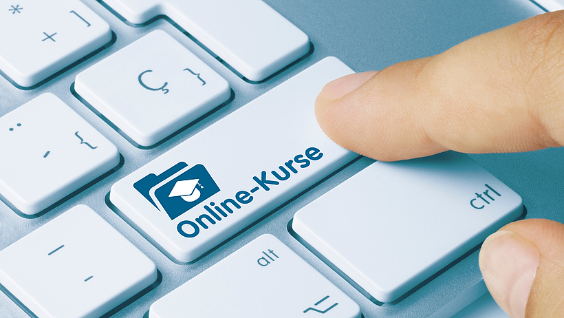 Ein Finger zeigt auf einer Tastatur auf eine Taste mit der Aufschrift „Online-Kurse“.
