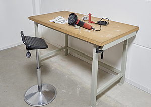 Eine ergonomisch höhenverstellbare Werkbank steht in einem Arbeitsraum um körperlichen Belastungen zu reduzieren.