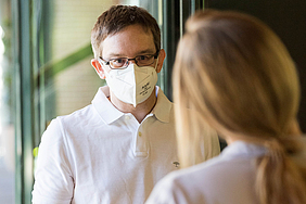 Ein Mann mit einer FFP2-Maske bietet ein Beratungsgespräch vor einer Impfungen an.