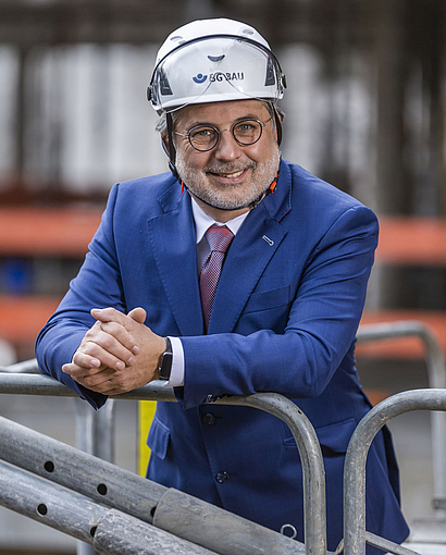 Der Hauptgeschäftsführer der BG BAU, Hansjörg Schmidt-Kraepelin mit Schutzhelm auf einer Baustelle.