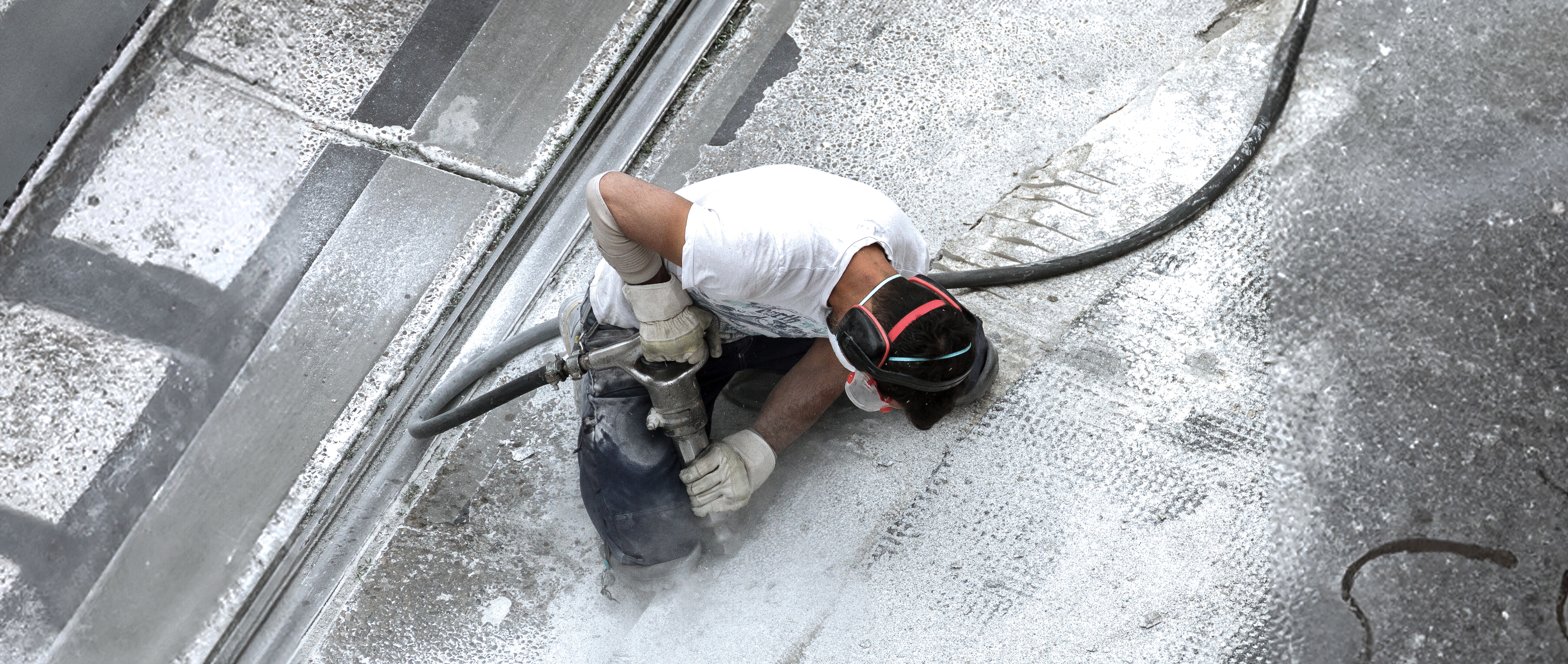 Ein Bauarbeiter arbeitet mit einem Presslufthammer aus der Vogelperspektive.