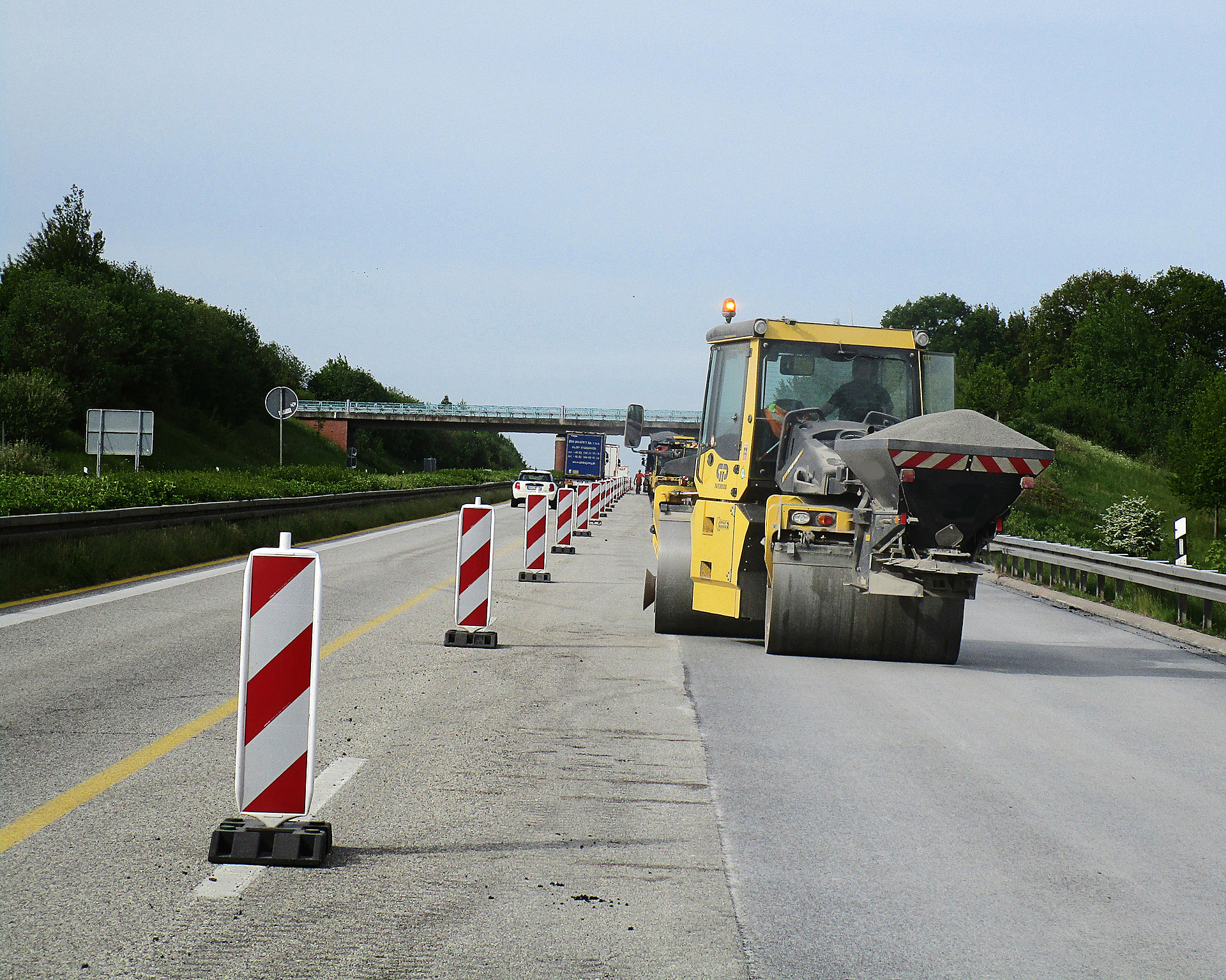 Eine Straßenwalze fährt über eine Baustelle auf der Autobahn.