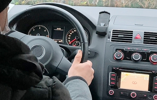 Fokus auf das Lenkrad im Auto, welches von einem Fahrer gehalten wird.