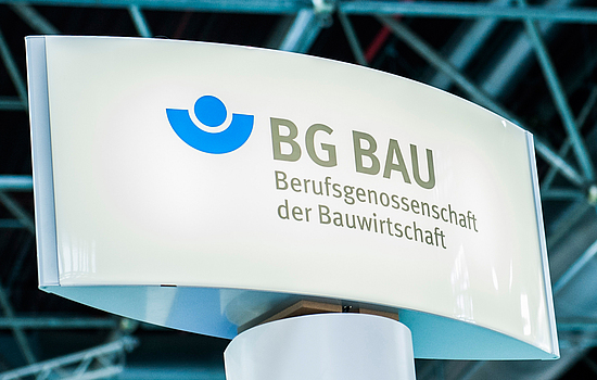 Weißes Schild mit BG BAU - Berufsgenossenschaft der Bauwirtschaft