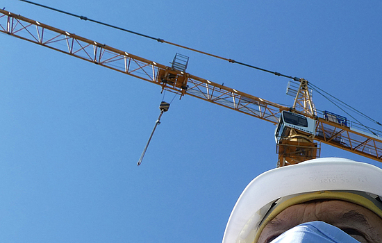 Ein Mann trägt einen medizinische OP-Maske auf einer Baustelle.