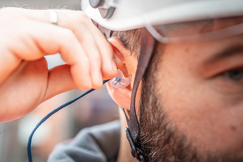 Eine Aufsichtsperson der BG BAU trägt Otoplastiken.