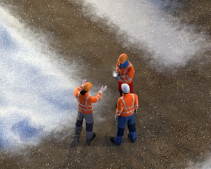 Illustration einer Baustelle im Winter: Blick von oben auf mehrere Bauarbeiter bei Schnee. Die Baustelle befindet sich inmitten einer Wohnanalage.