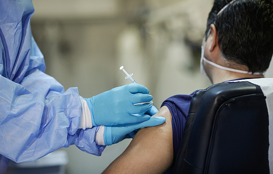 Ein Mann wird von einem medizinischem Personal gegen das Coronavirus geimpft.