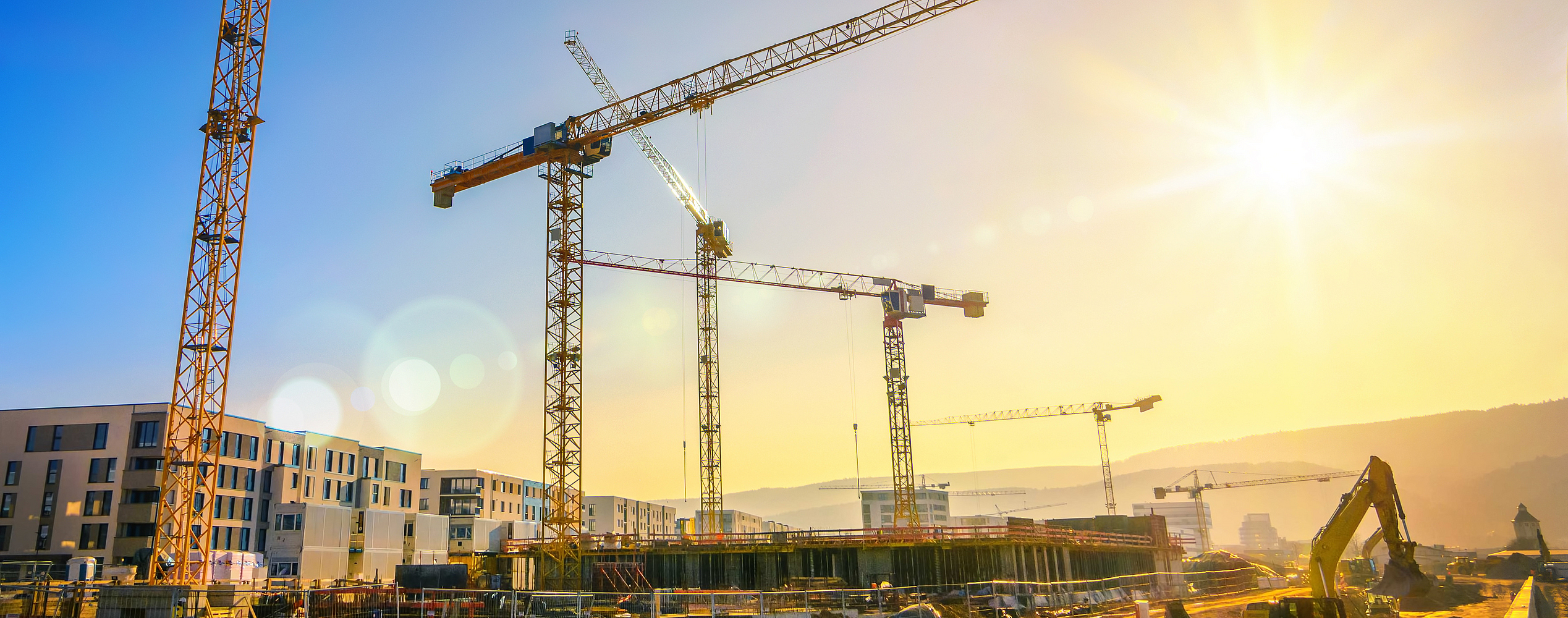Eine Baustelle mit mehreren Kränen, die an einem Gebäudekomplex arbeiten.