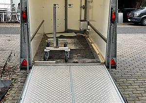 Ein Anhänger ist auf Bodenniveau abgesenkt - mit begehbarer und befahrbarer Ladefläche.