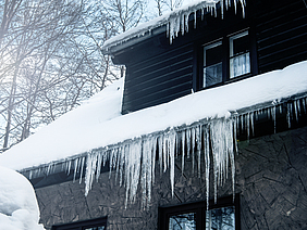 Ein Dach voller Schnee mit Eiszapfen.