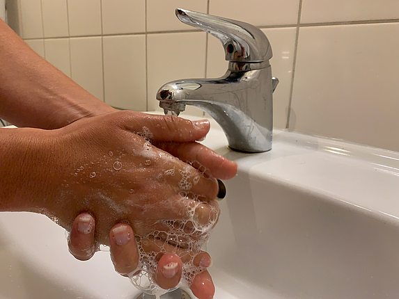 Fokus auf zwei Hände einer Person, die sich die Hände im Waschbecken einseift