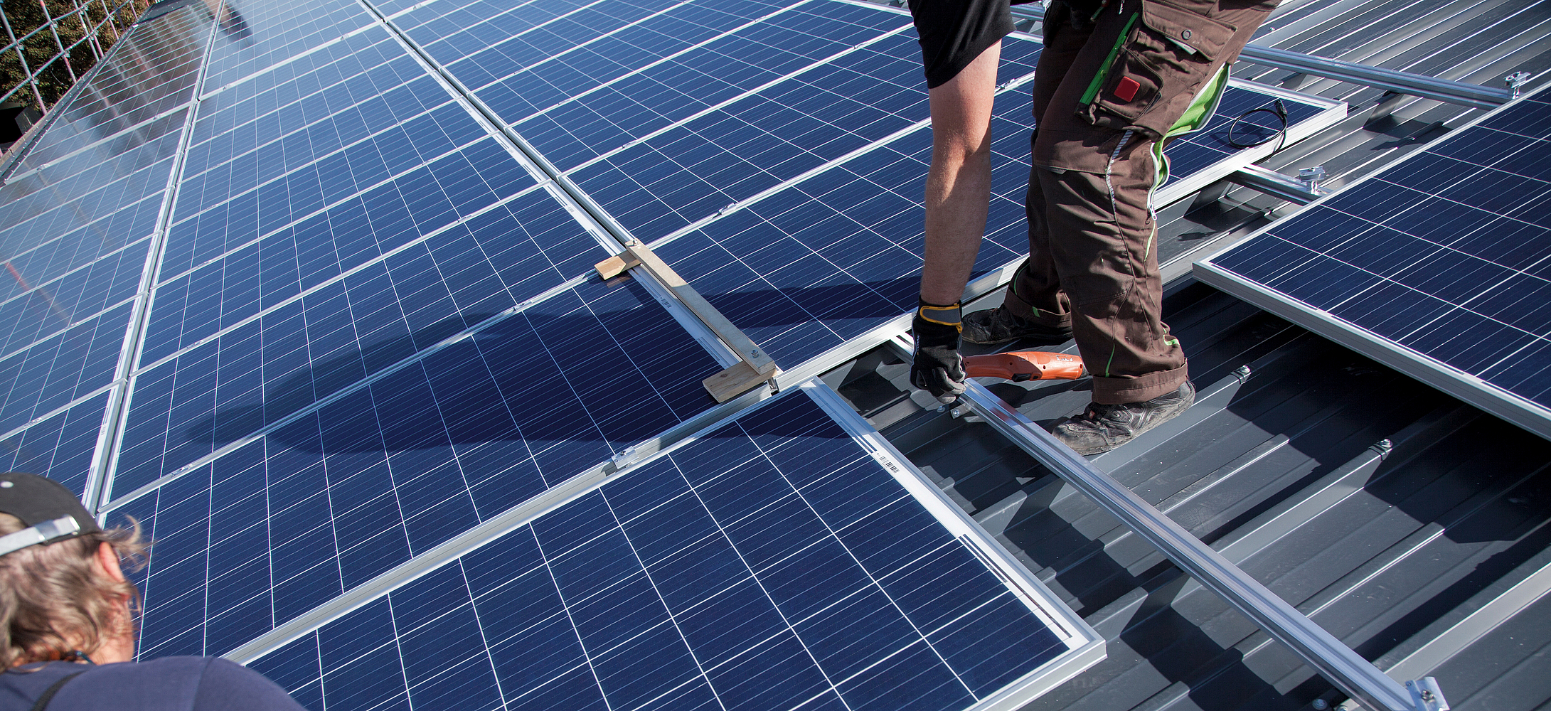 Photovoltaikmodule werden von zwei Arbeitern auf einem Steildach installiert.