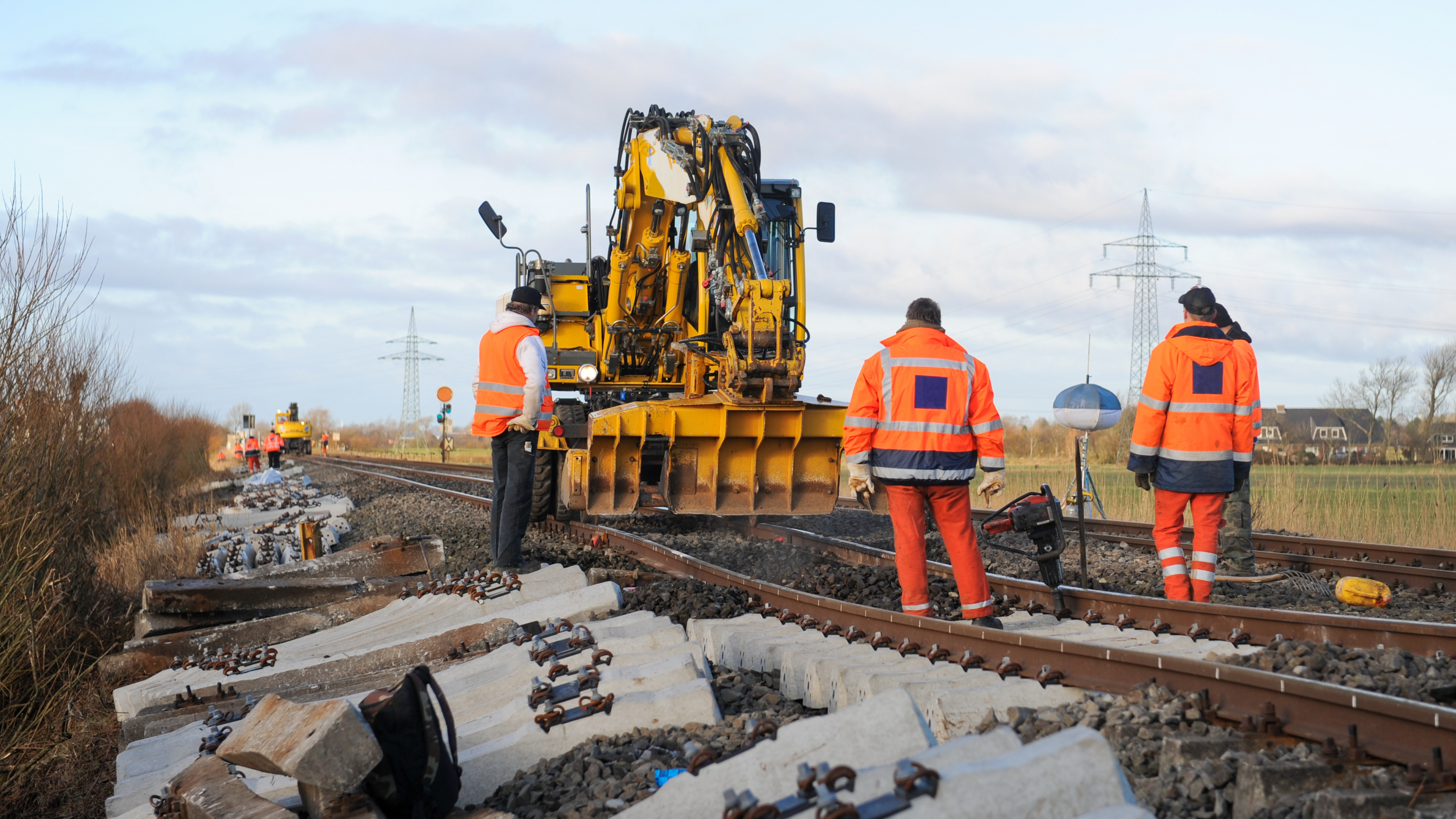 Mehrere Bauarbeiter arbeiten an einem Bahngleis. 