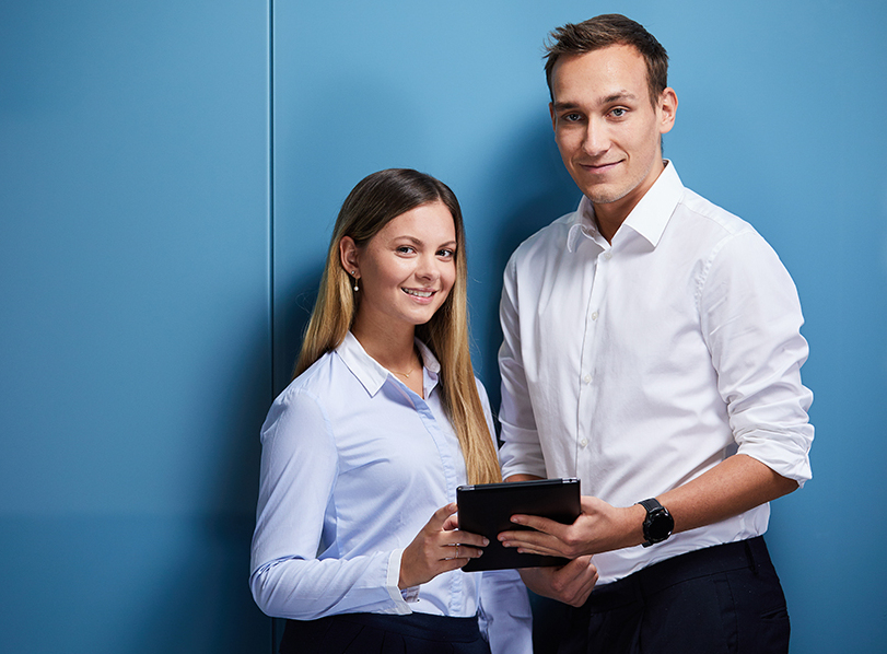Eine junge Frau und ein junger Mann halten gemeinsam ein Tablet in der Hand.