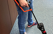Eine Person bedient einen Bewehrungsstahlschneider mit Armstütze, um auf dem Boden liegenden Bewehrungsstahl zu schneiden.