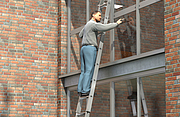 Ein Mann auf einer Stufen-Glasreinigerleiter bei der Glasreinigung