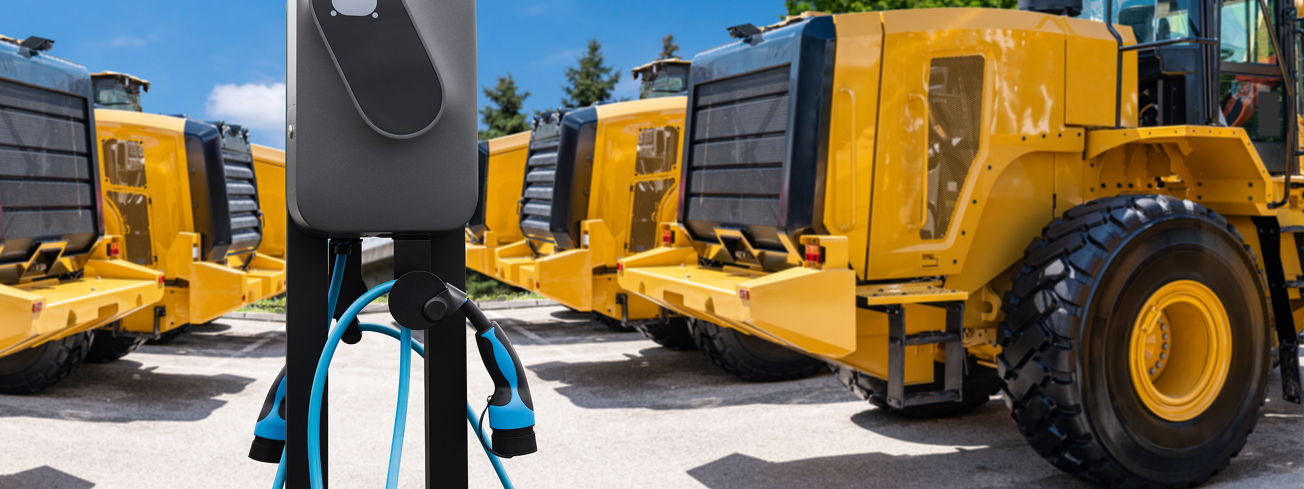 Mehrere Radlader stehen um eine Ladesäule herum.