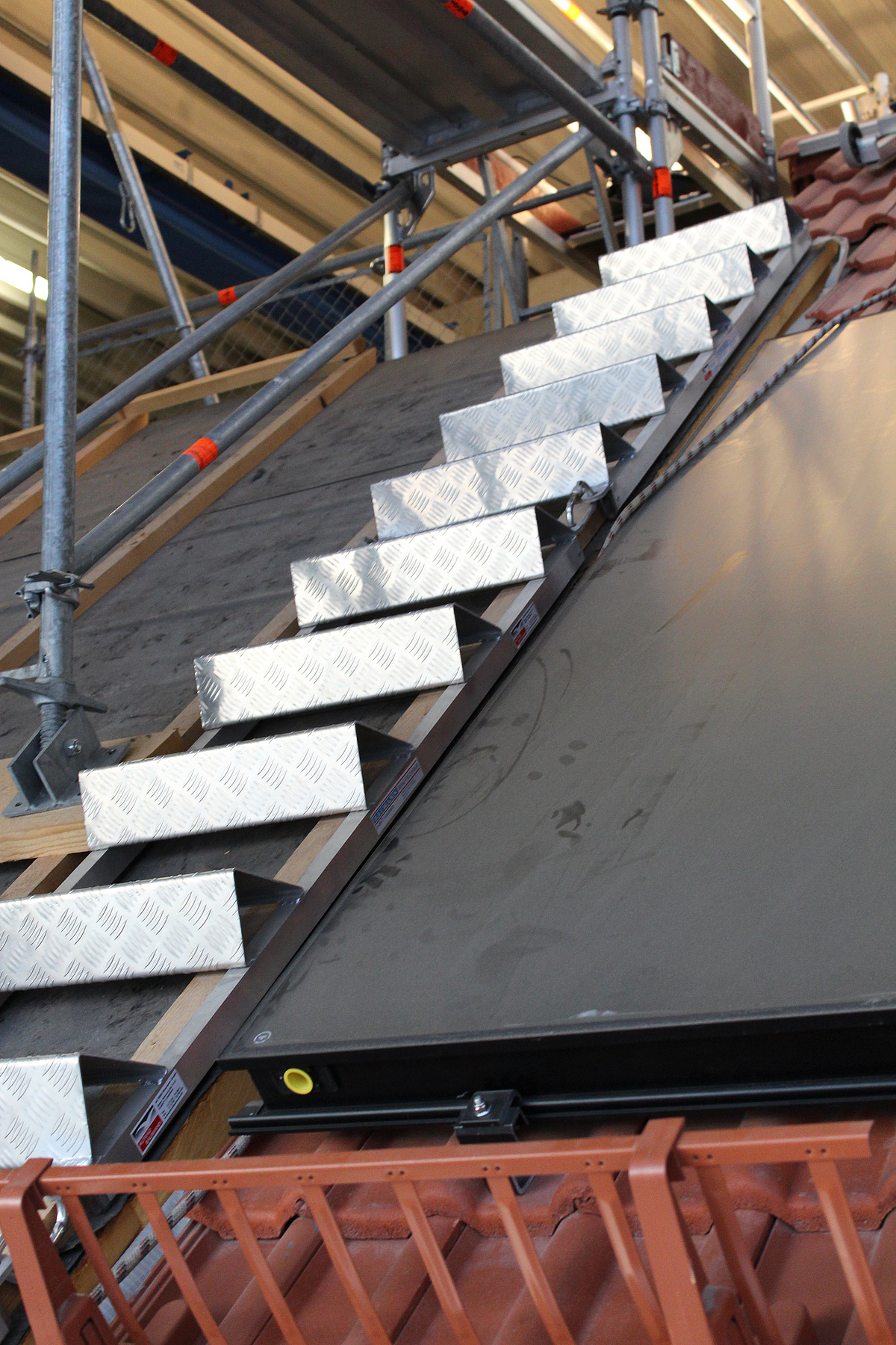 Eine Stufen-Auflegeleiter liegt auf einem Dach. Sie erleichtert den Zugang und die Durchführung von Dacharbeiten.