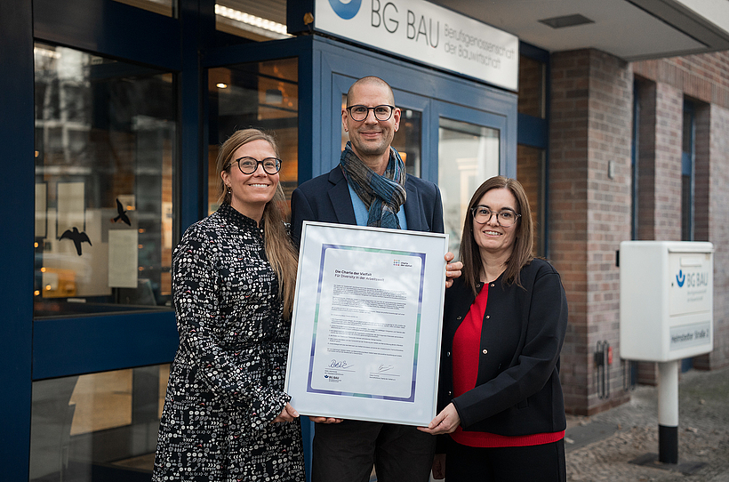 Die stv. Hauptgeschäftsführerin der BG BAU Katia-Julia Rostek (links im Bild) mit Alexandra Schlosser, Inklusionsbeauftragte der BG BAU, sowie Thomas Kampe, Vielfaltsbeauftragter der BG BAU, mit der Beitrittsurkunde „Die Charta der Vielfalt“ Die stellvertretende Hauptgeschäftsführerin der BG BAU Katia-Julia Rostek (links im Bild) mit Alexandra Schlosser, der Inklusionsbeauftragten der BG BAU und Thomas Kampe aus dem Referat Organisationsentwicklung halten die Beitrittsurkunde „Die Charta der Vielfalt“.