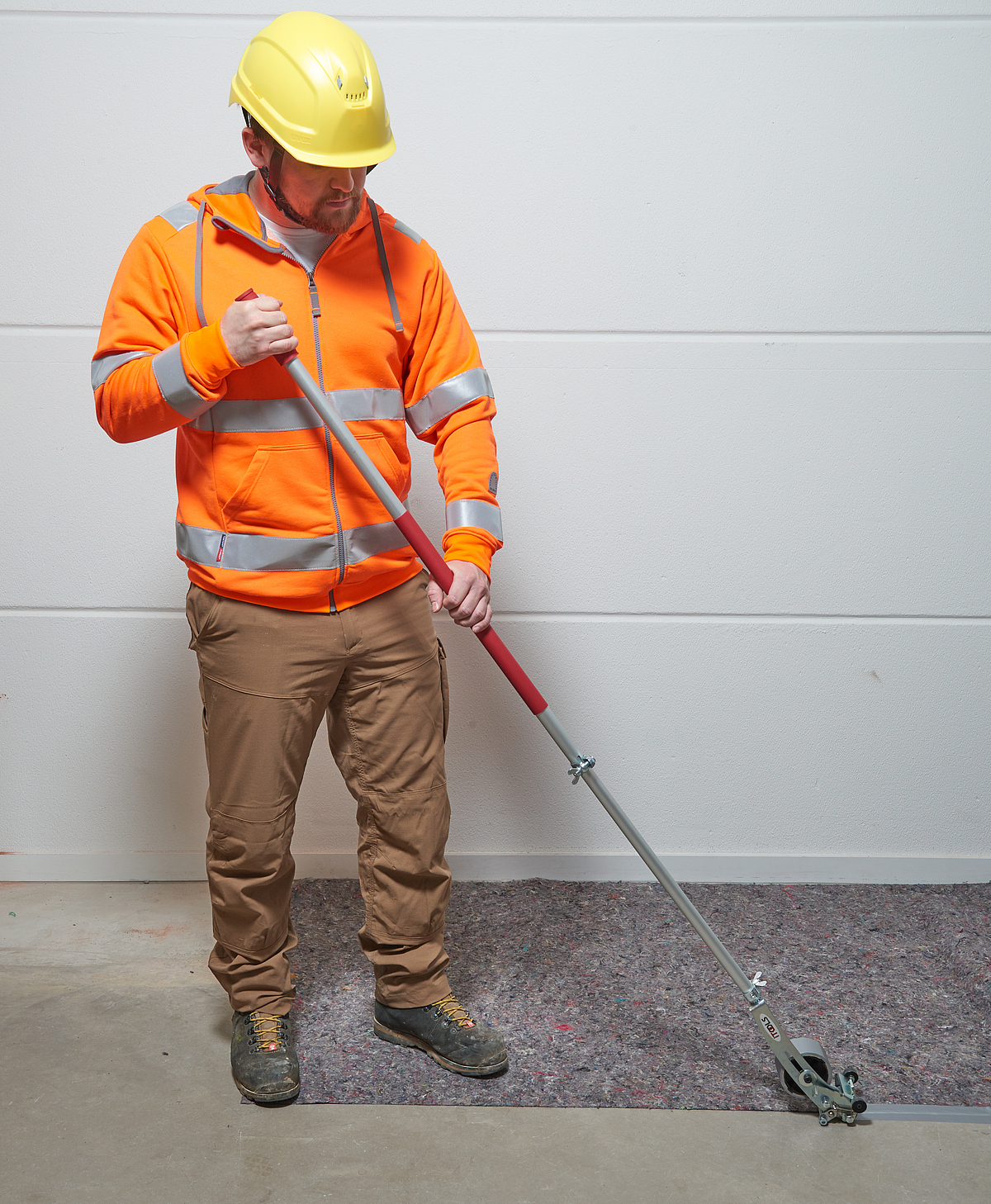 Ein Mann bedient per Teleskopstiel ein Werkzeug am Boden