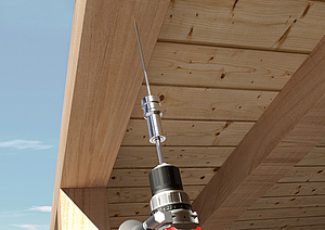 Eine Einschraubhilfe stabilisiert eine lange Holzbauschraube, die mit einem Akkuschrauber senkrecht in eine Holzdecke eingedreht wird.
