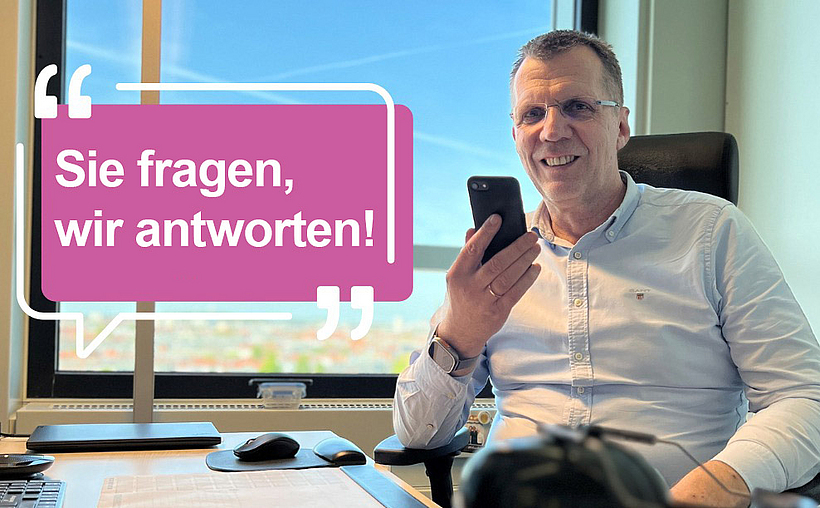 Prof. Werner sitzt am Schreibtisch und hält sein Handy in der Hand.