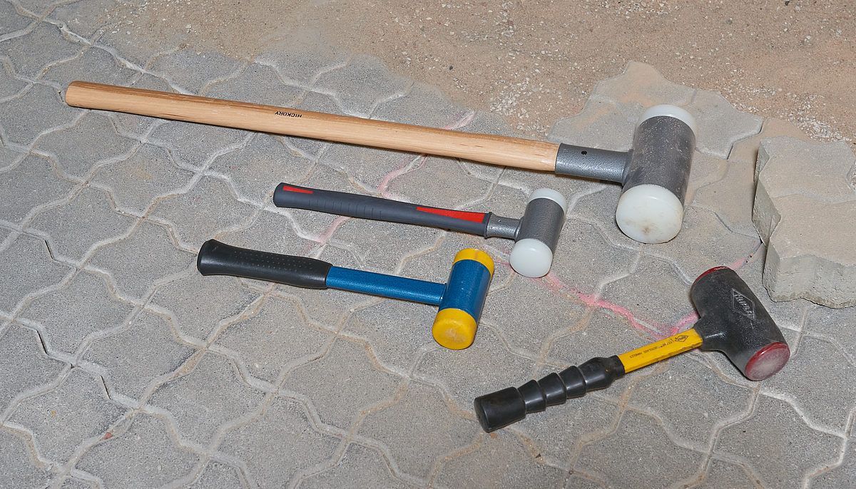 Eine Auswahl von vier verschiedenen rückschlagfreien Hammer liegen auf einem Steinboden.