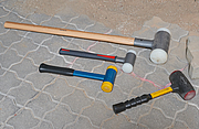 Eine Auswahl von vier verschiedenen rückschlagfreien Hammer liegen auf einem Steinboden.