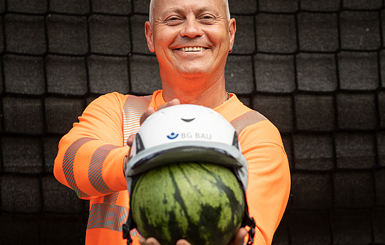 Die Aufsichtsperson Denny Hillert zeigt anhand einer Melone wie gut ein Schutzhelm den Kopf schützt.