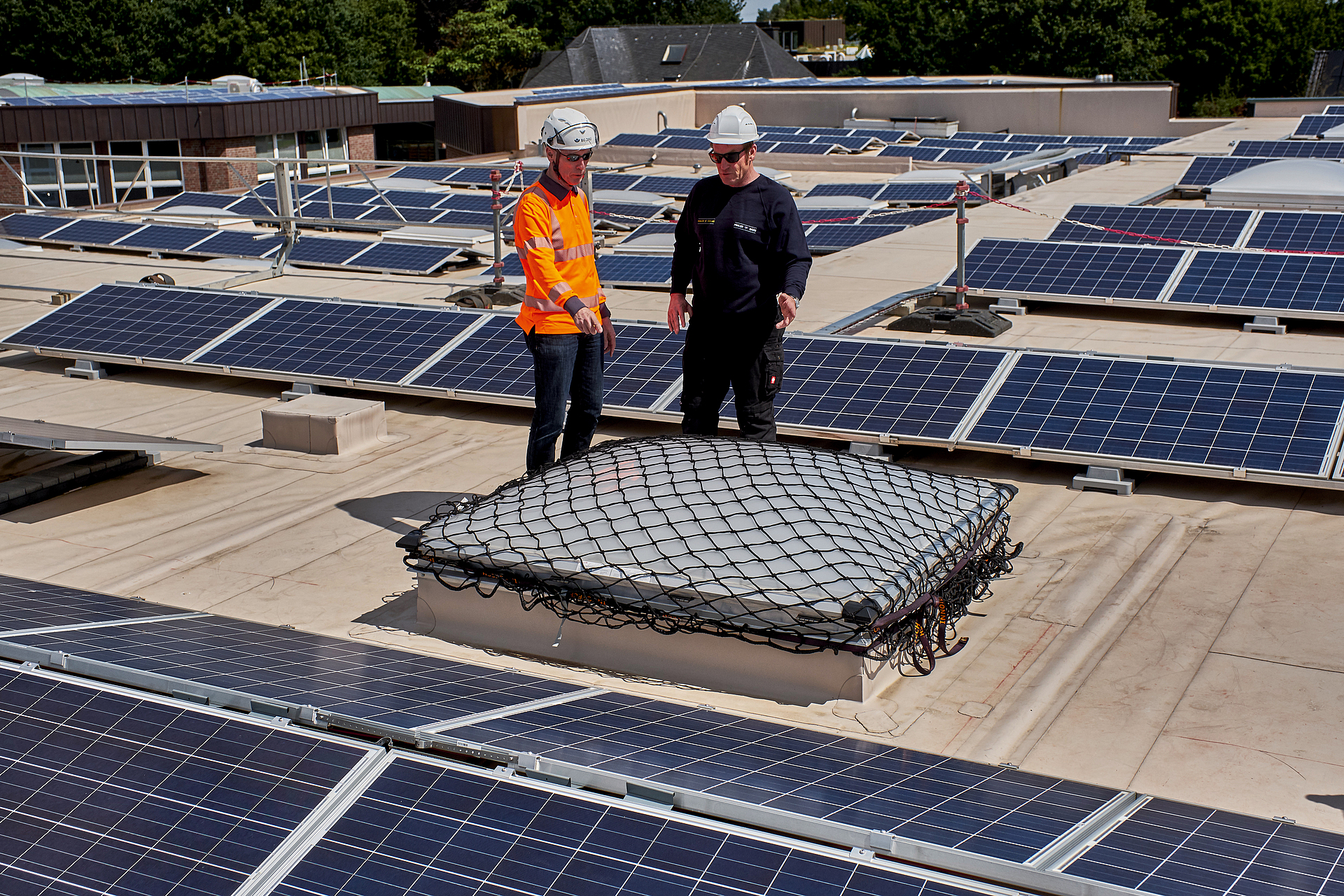 Eine Aufsichtsperson und ein Beschäftigter sprechen über die gesicherte Lichtkuppel auf einem Dach. 