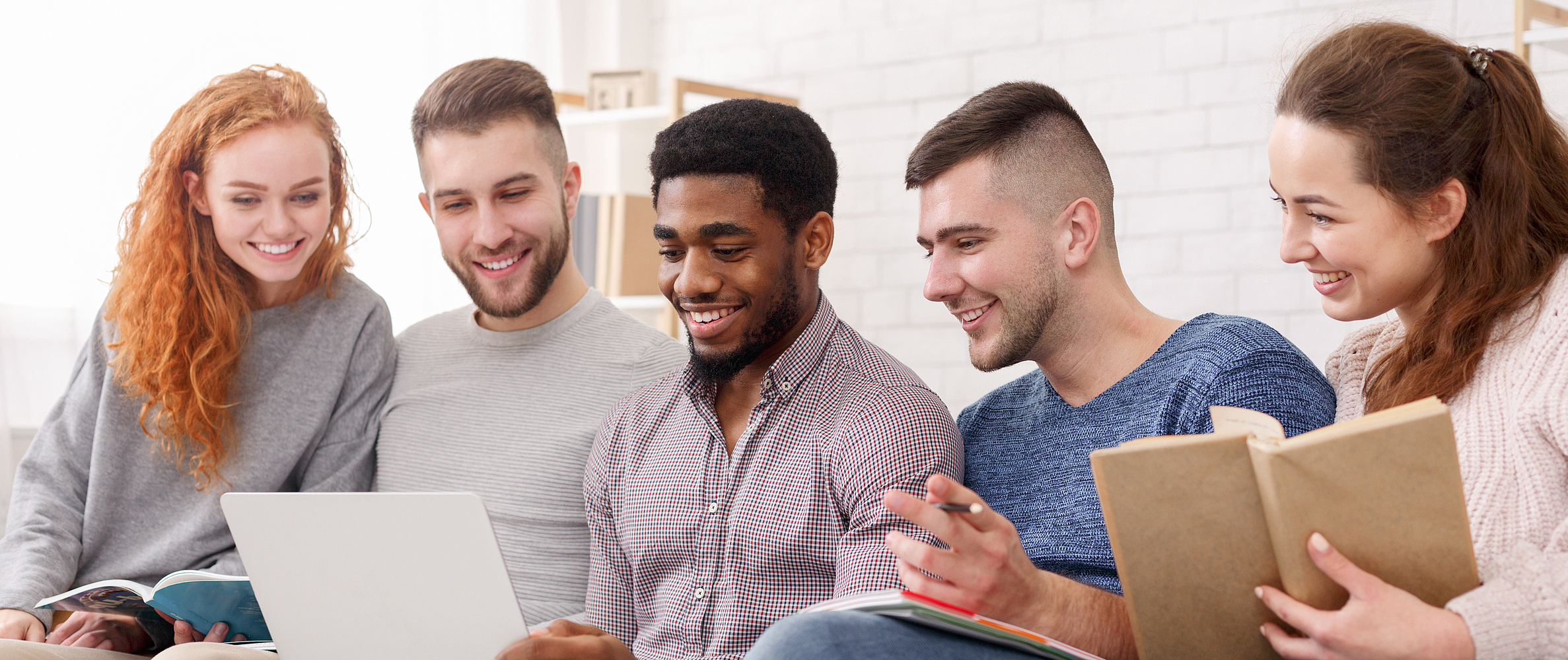 Junge Menschen sitzen auf der Couch vor einem Laptop.