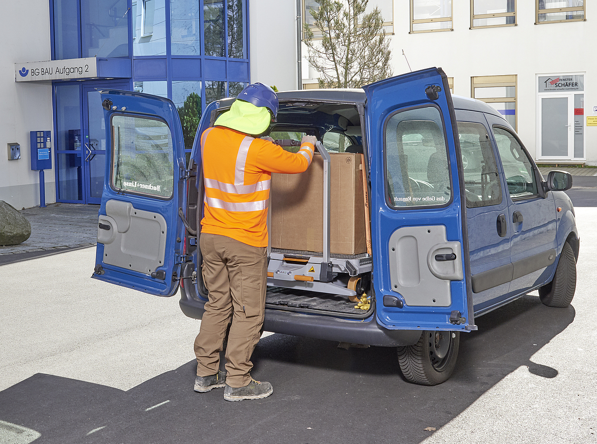 Ein Mann belädt die Last vollständig in das Fahrzeug mithilfe eines elektrohydraulischen Systems des Transportwagens mit Hebehilfe 