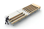 Auf einem Montagetisch wird ein Wanddecken- oder Dachelement aus Holz von einer Person vorgefertigt.