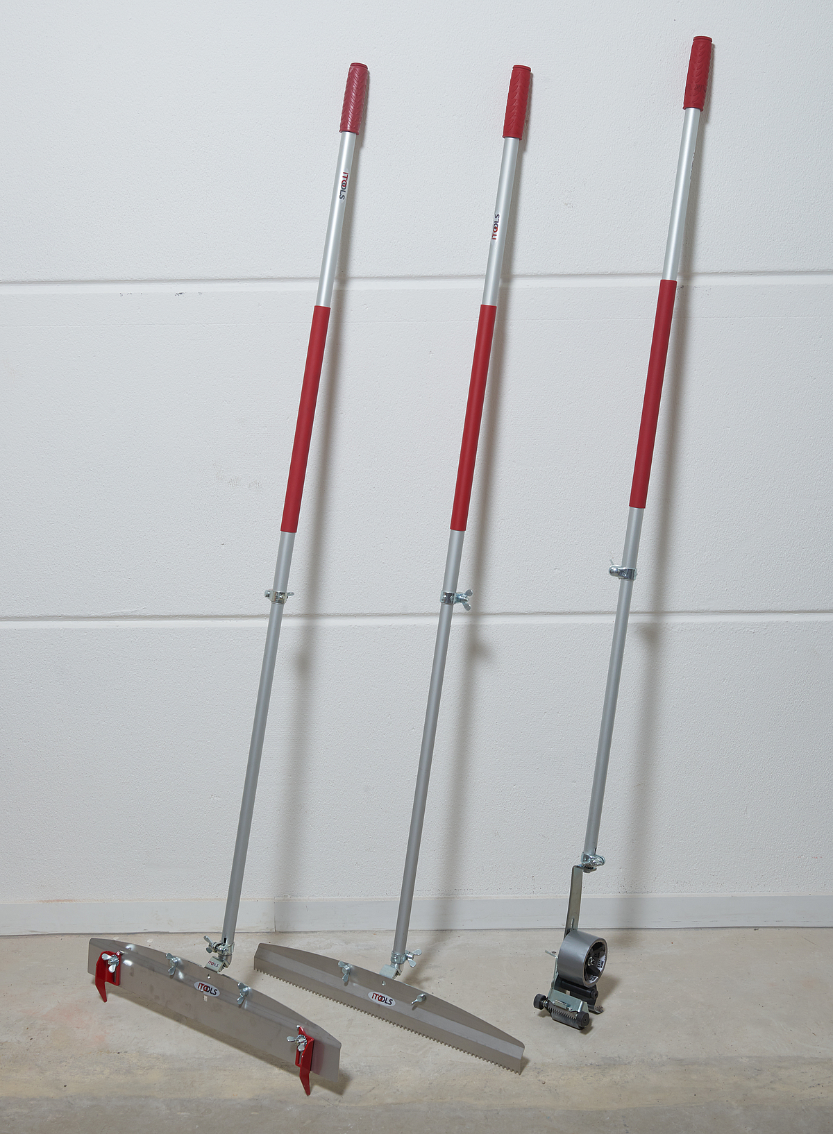 Drei Werkzeuge mit Teleskopstiel lehnen an einer Wand