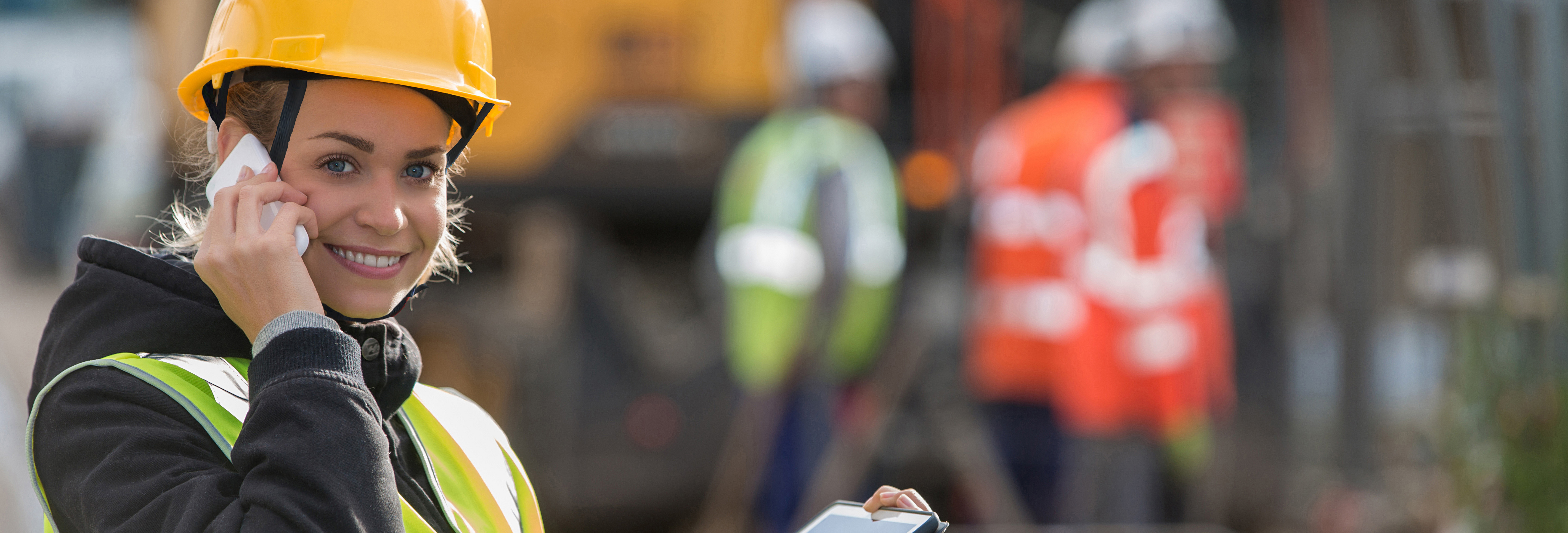 Eine Bauarbeiterin telefoniert auf einer Baustelle.