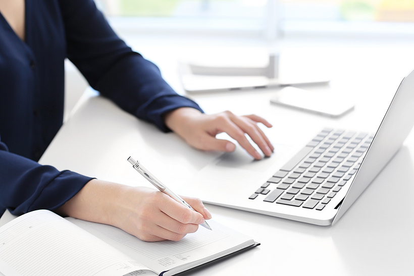 Junge Frau, die am Schreibtisch einen Laptop für die Suche von Informationen im Internet verwendet