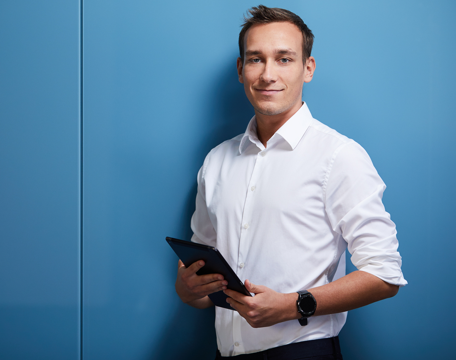 Ein junger Mann hält ein Tablet in der Hand.