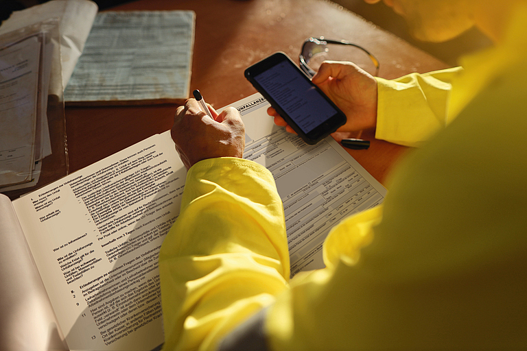 Eine Person füllt per Telefon ein Formular zur Unfallmeldung aus.