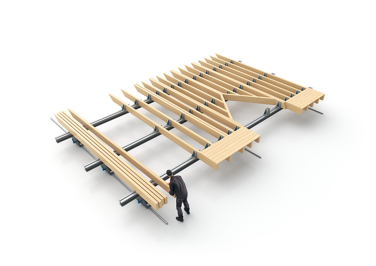 Auf einem großen Montagetisch wird ein Wanddecken- oder Dachelement aus Holz von einer Person vorgefertigt.