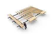 Auf einem großen Montagetisch wird ein Wanddecken- oder Dachelement aus Holz von einer Person vorgefertigt.