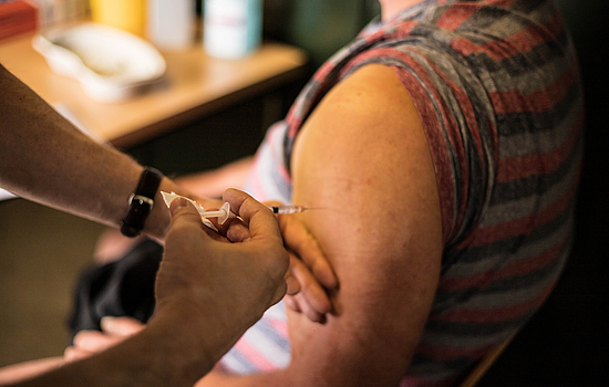 Ein Mann erhält eine Impfung in einen Oberarm.